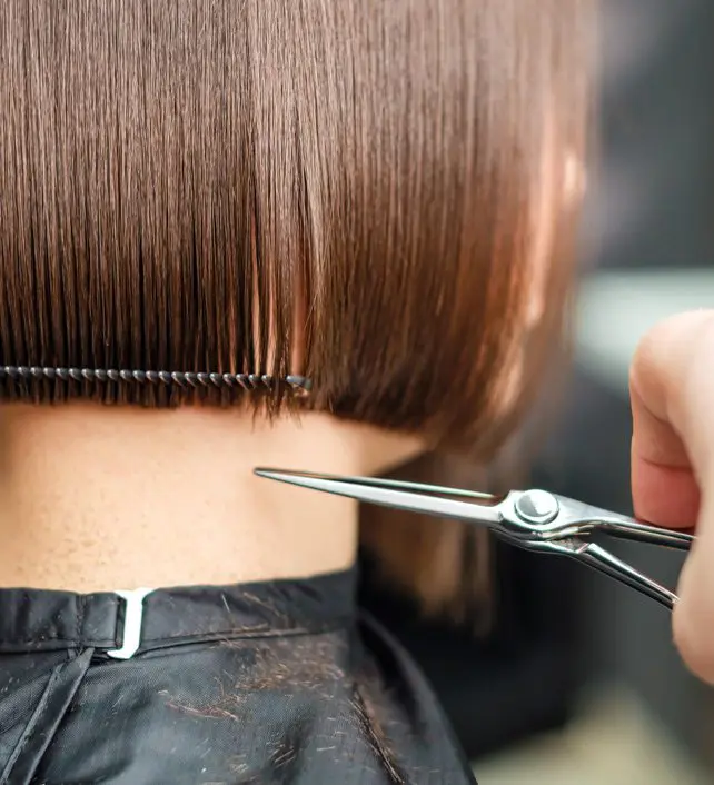 Woman getting a haircut with scissors.